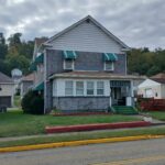 A house with a green awning on the front, providing shade and adding a touch of color to the facade.