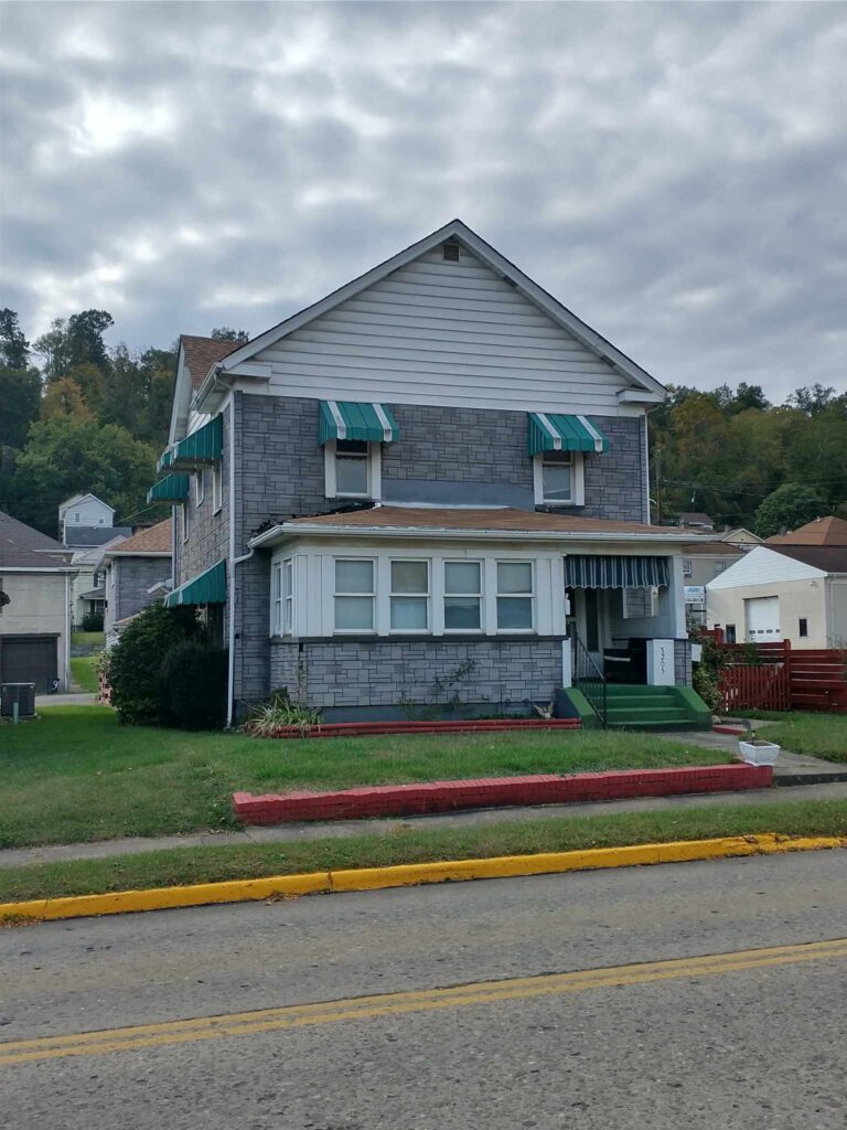 A house with a green awning on the front, providing shade and adding a touch of color to the facade.