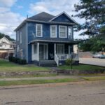 A charming blue house with a porch and a white picket fence, creating a picturesque and inviting scene.