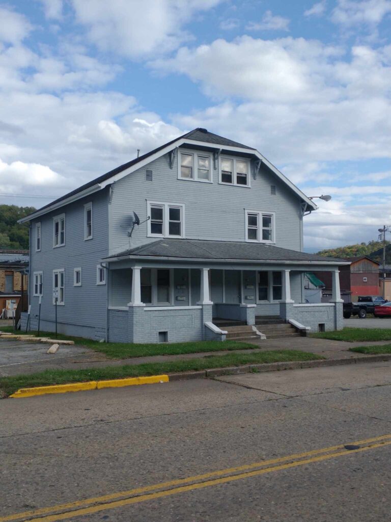 A spacious gray house with a white roof stands tall, exuding elegance and charm.