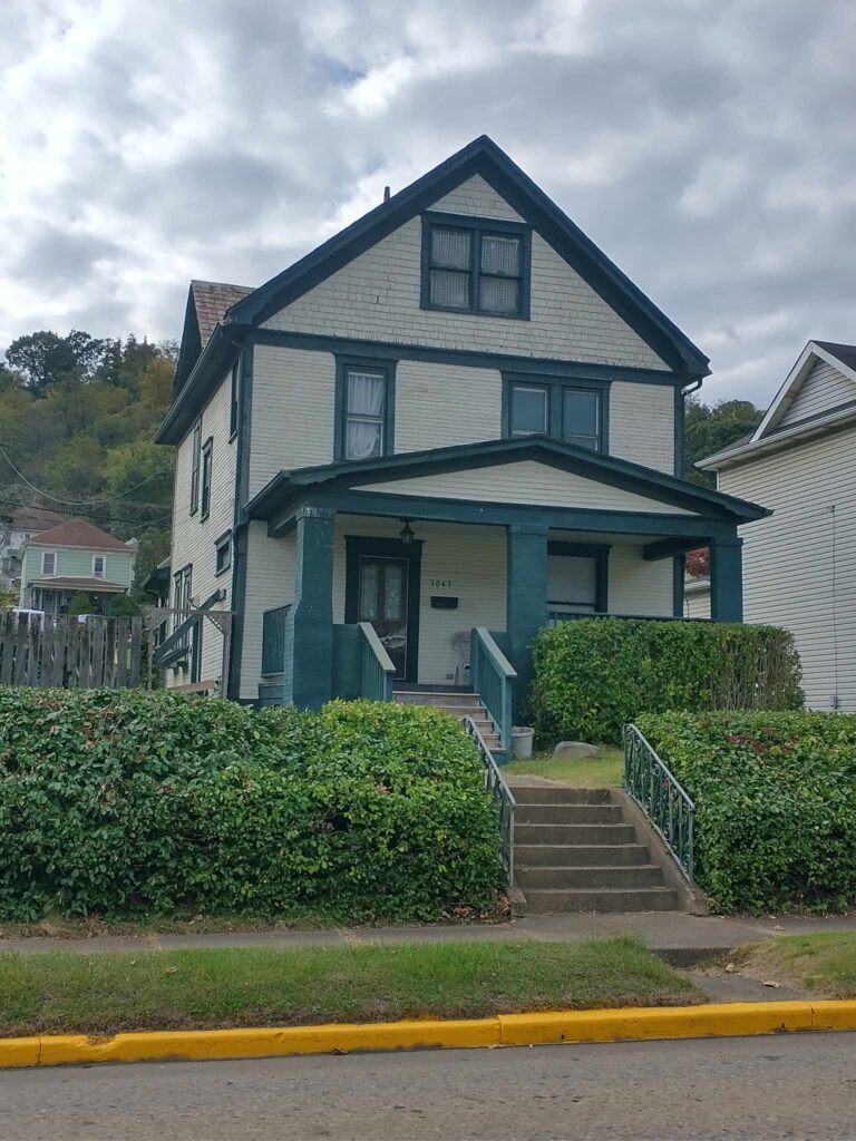 Two-story house with front porch and yard.