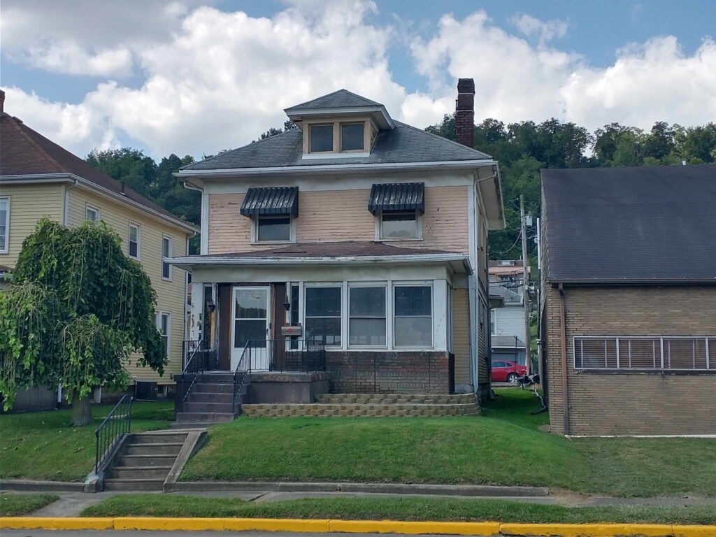 A charming two-story brick house with a porch and a front yard, exuding a sense of warmth and homeliness.