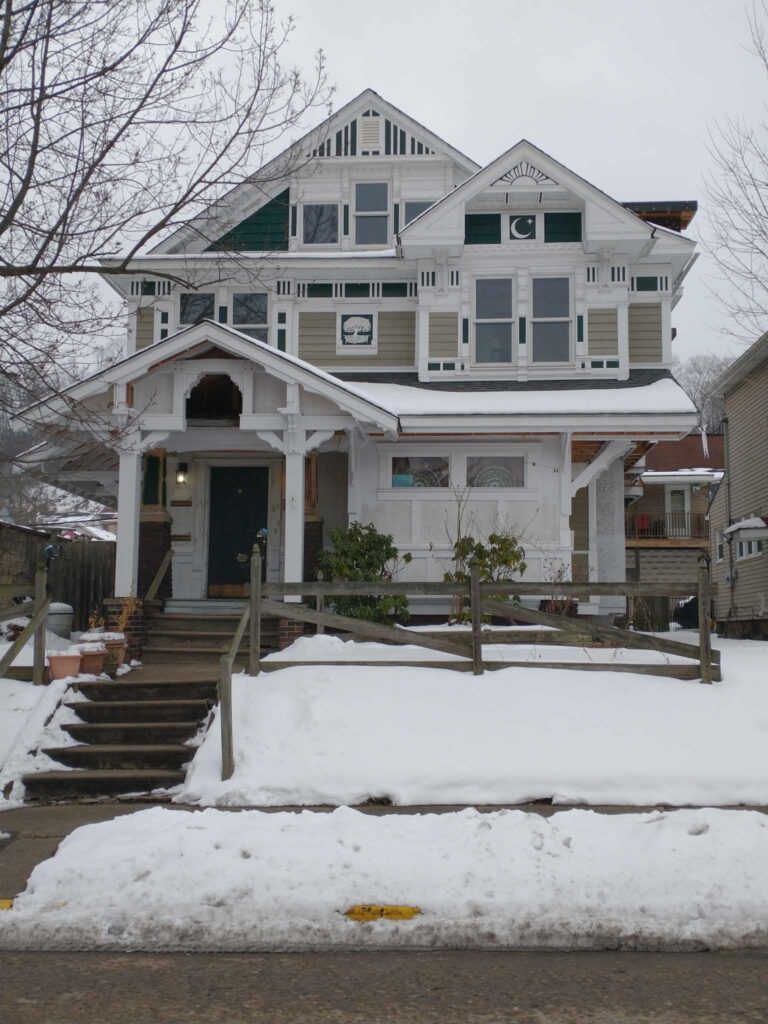 Spacious house with white roof and green porch, surrounded by snow-covered yard.