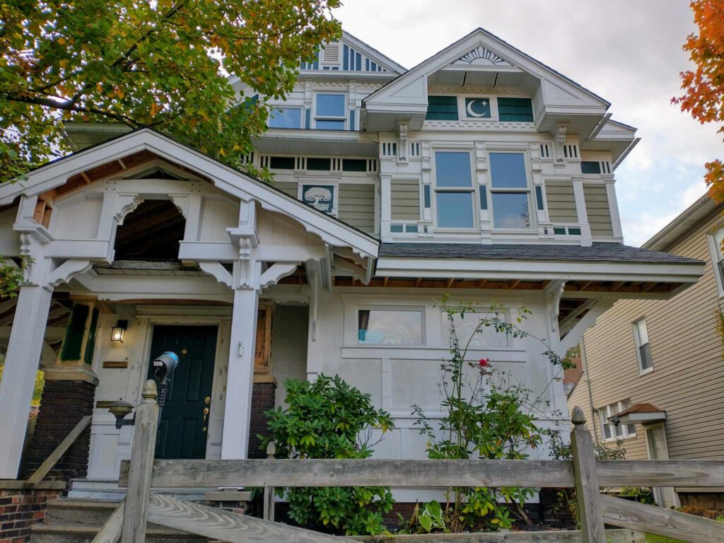 A charming two-story house with a welcoming porch and a white picket fence surrounding it.