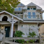 A charming two-story house with a welcoming porch and a white picket fence surrounding it.