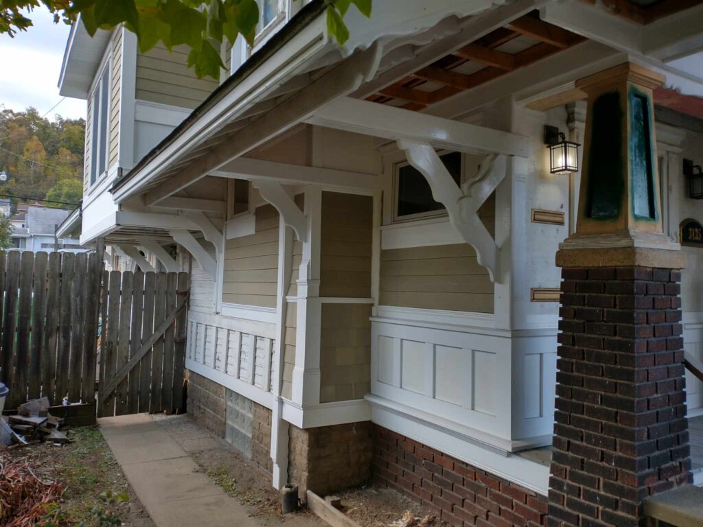 A white house with a wooden fence and porch, showcasing a charming blend of elegance and rusticity.