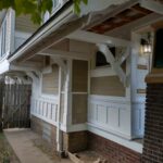 A white house with a wooden fence and porch, showcasing a charming blend of elegance and rusticity.