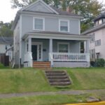 Charming gray house with inviting white porch.